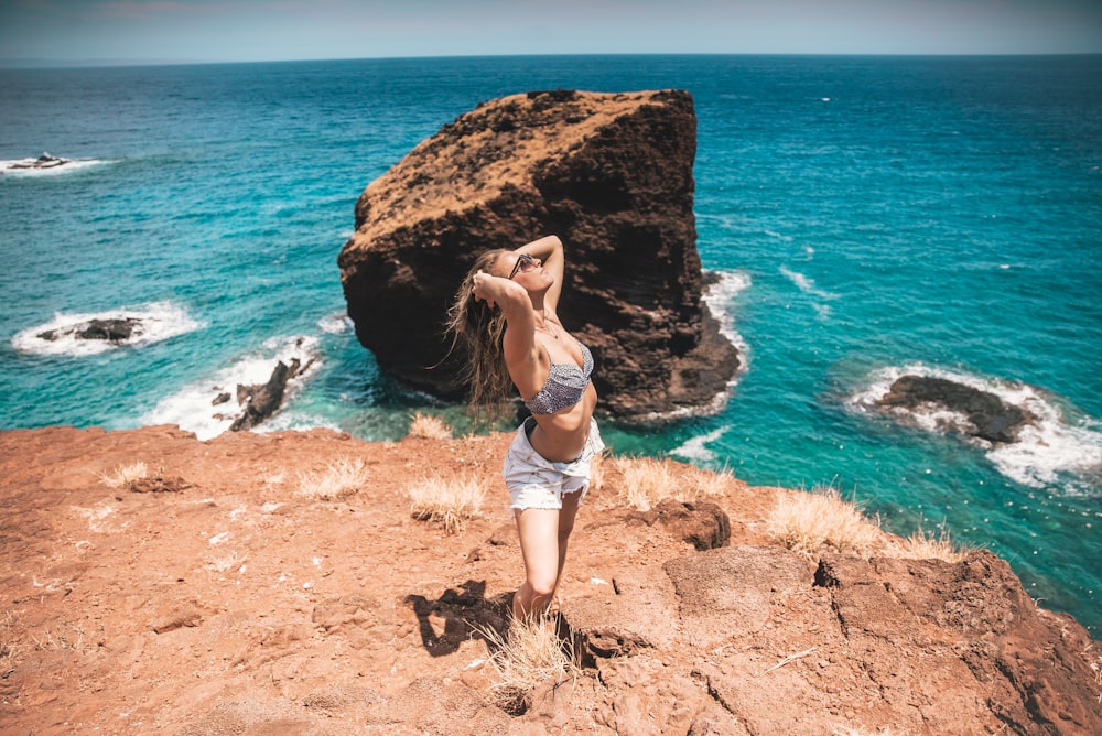 woman standing on brown soil in front blue ocean water