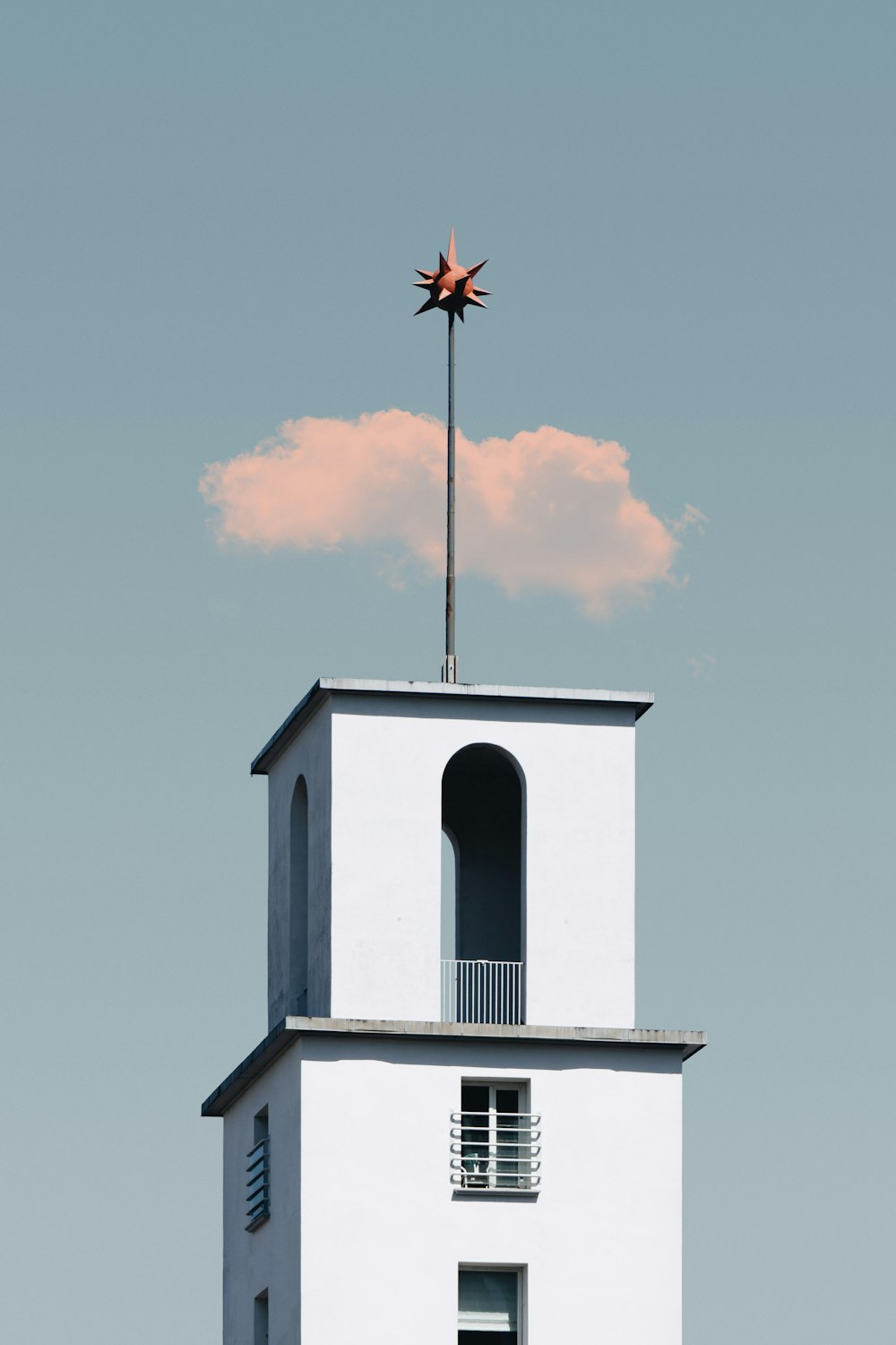 white concrete tower with star-like topper under cloudy blue sky