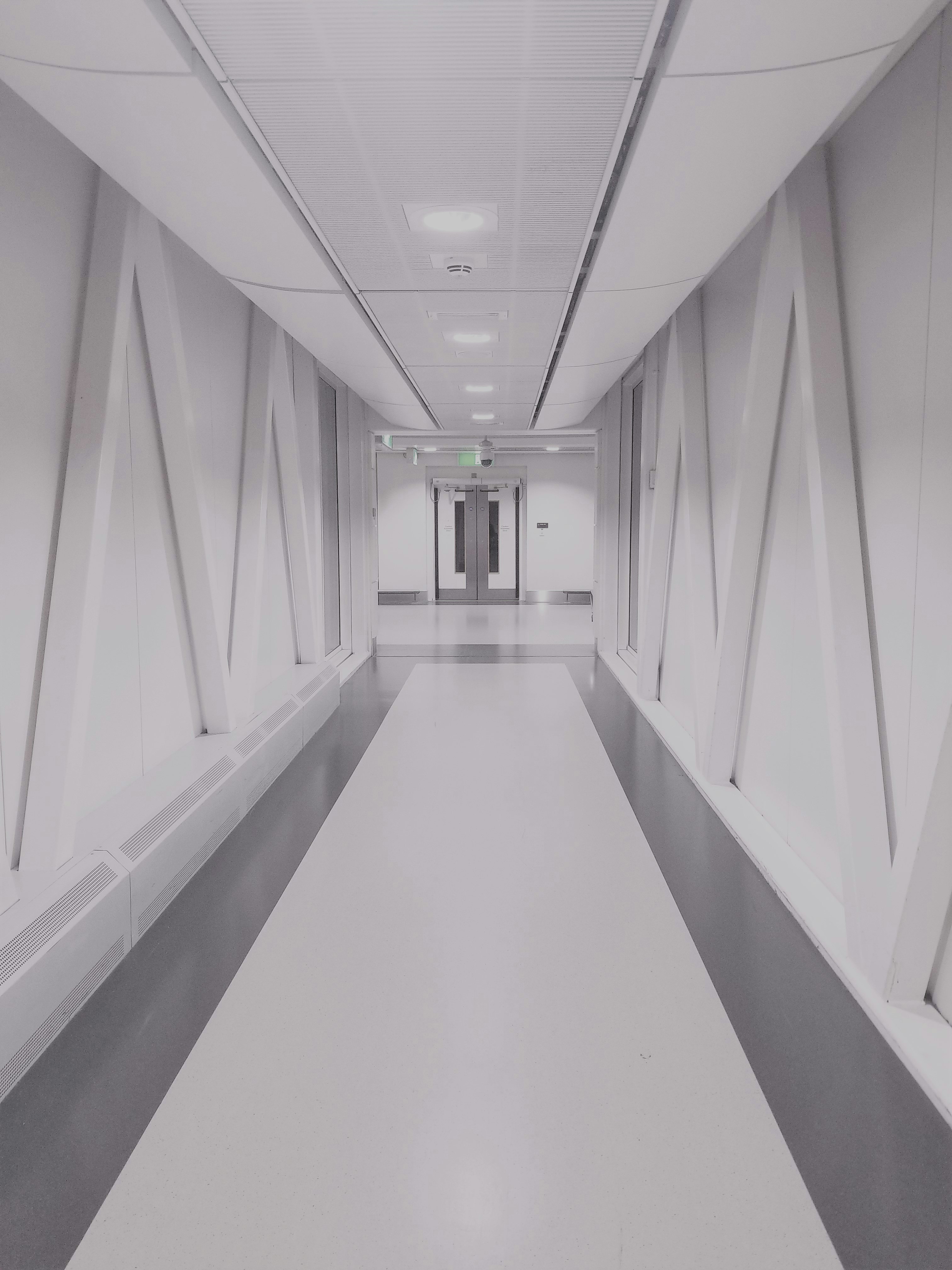 person taking photo of white and gray hallway
