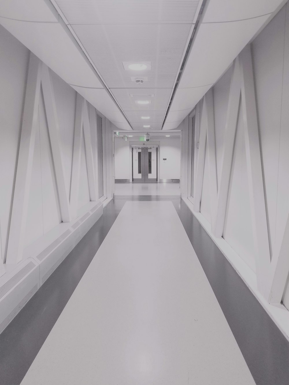 person taking photo of white and gray hallway
