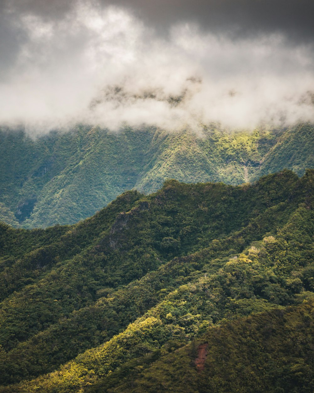 white clouds above green mountain