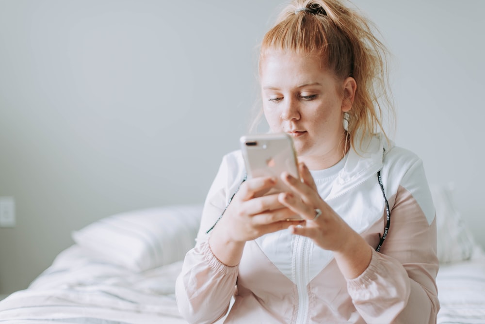 woman sitting on bed while using gold turned 8 Plus