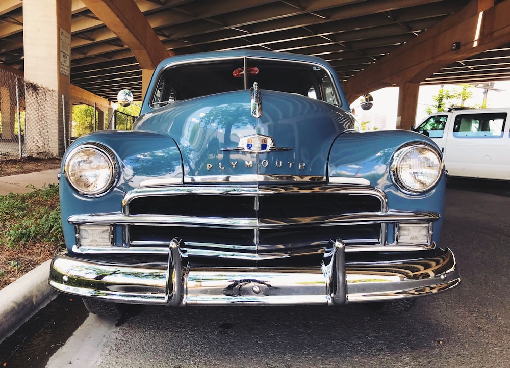 blue Plymouth car on gray concrete pavement during daytime