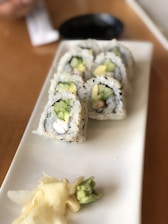 Close-up of colorful maki rolls arranged on a wooden platter with wasabi and ginger.