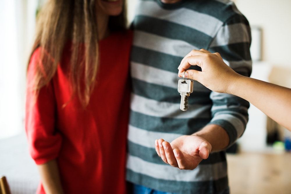 person hanging keys to man's hand standing next to girl