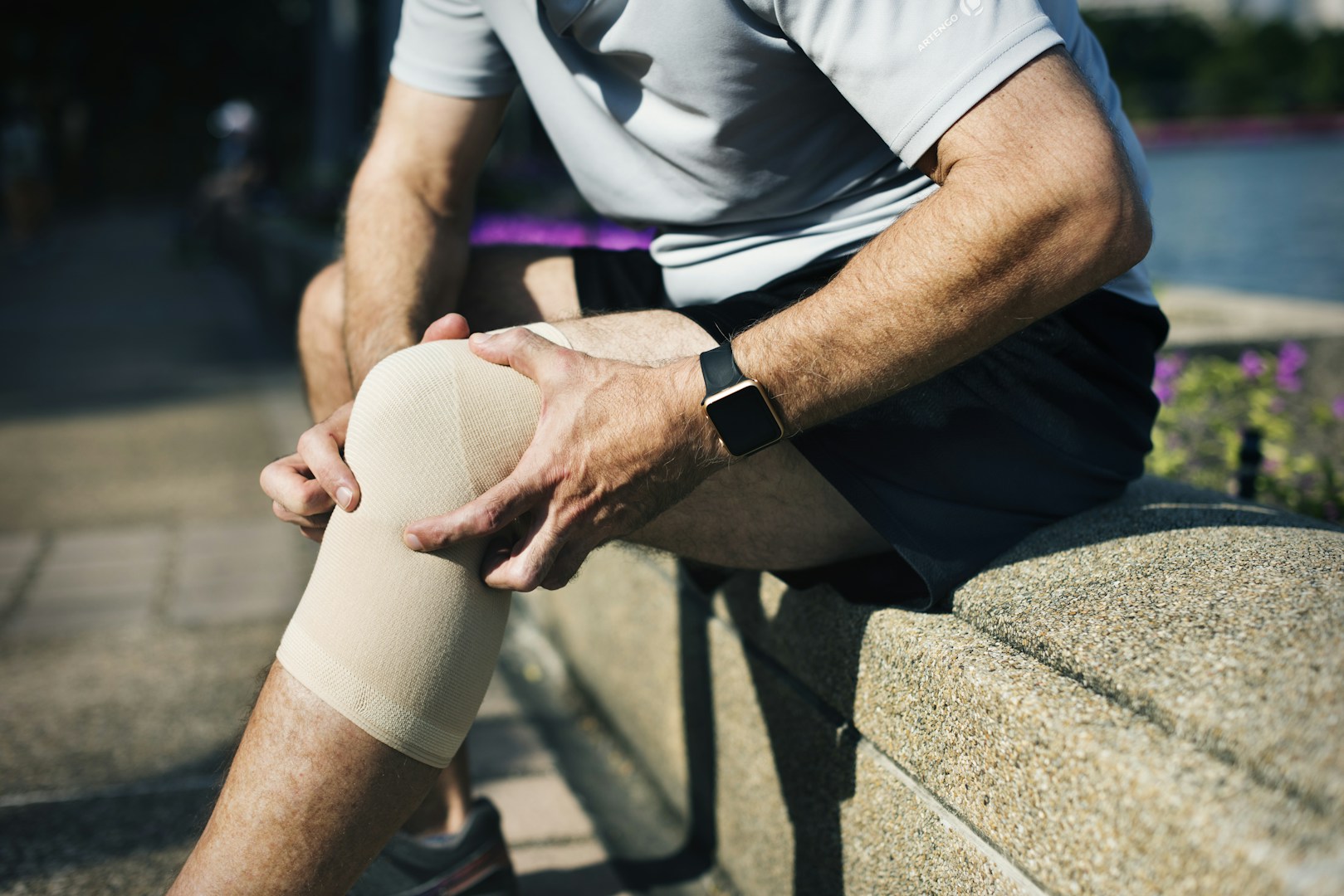 man with knee arthritis sitting down wearing a knee brace
