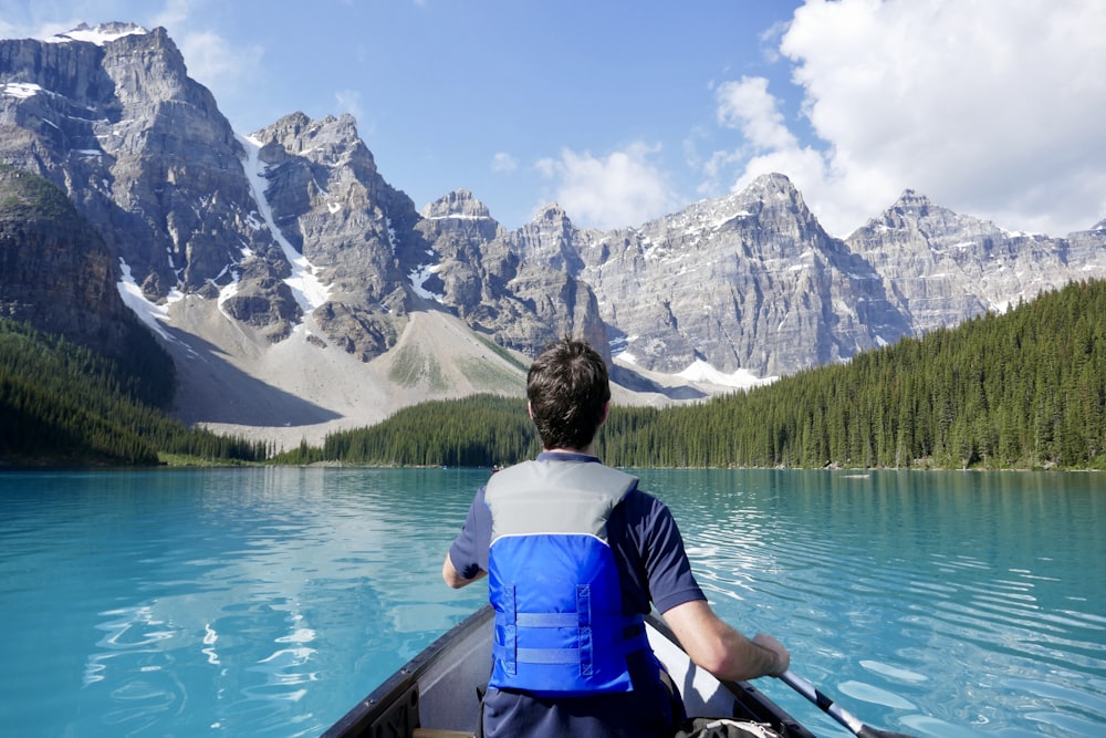 man kayaking near mountain and forest