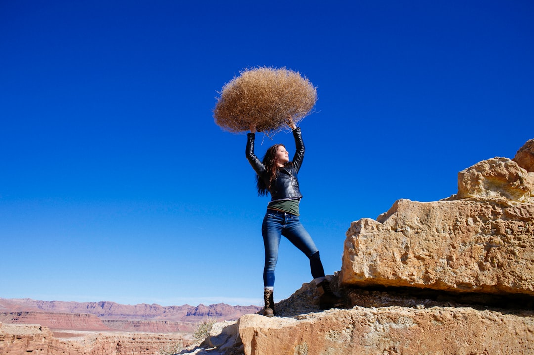 woman standing on rock formation while carrying hay during daytime