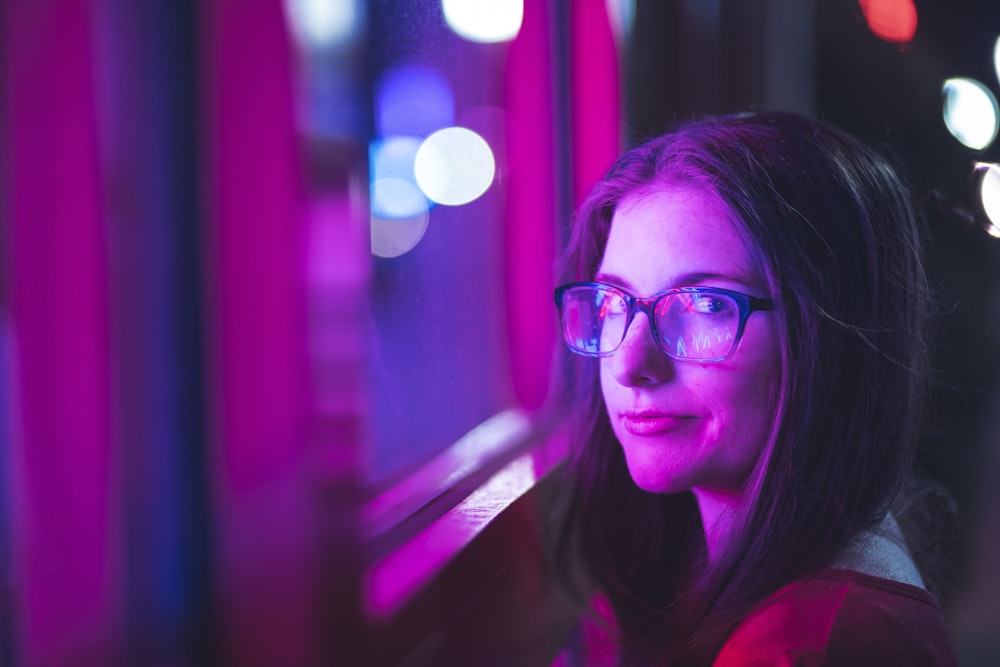 woman wearing eyeglasses standing beside glass window