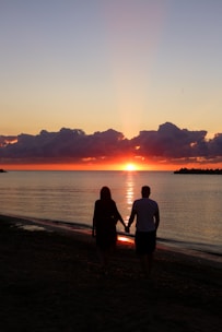 Happy couple holding hands on a tropical beach during sunset.