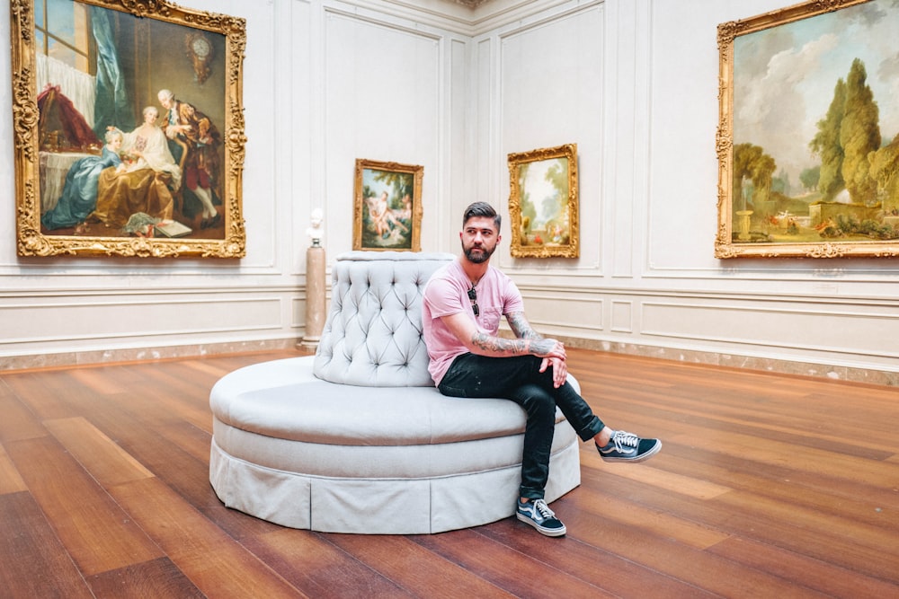 Uomo seduto sul divano bianco all'interno della stanza d'arte
