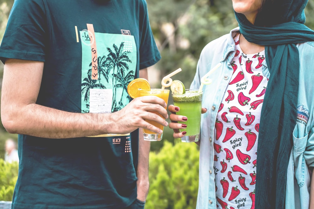 man and woman standing while holding drinking glasses during daytime