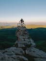man holding bike while standing on gray mountain