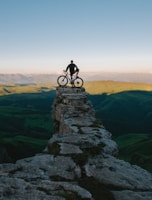 man holding bike while standing on gray mountain