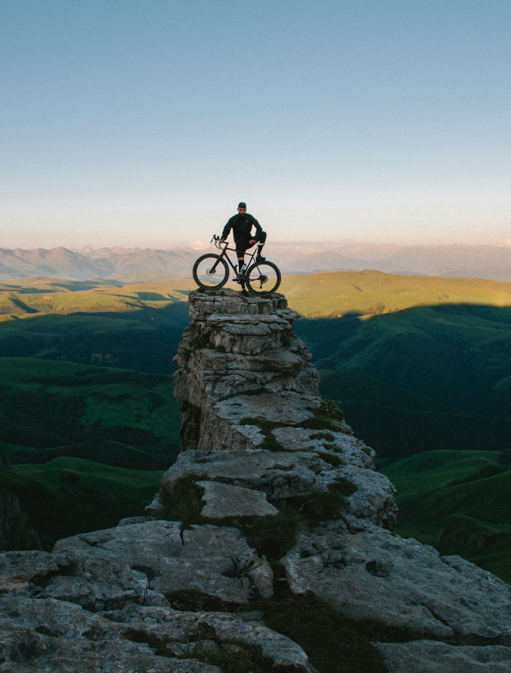 灰色の山に立って自転車を持つ男