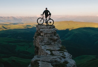 man holding bike while standing on gray mountain