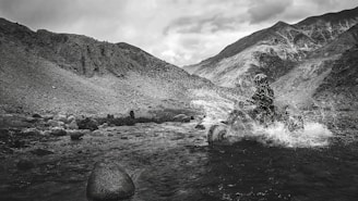 Smiling rider crossing a shallow stream with splashing water around the ATV tires