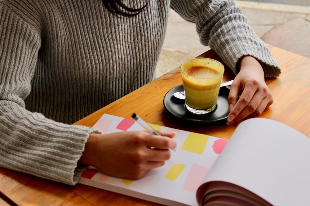 person holding pen with coffee on table