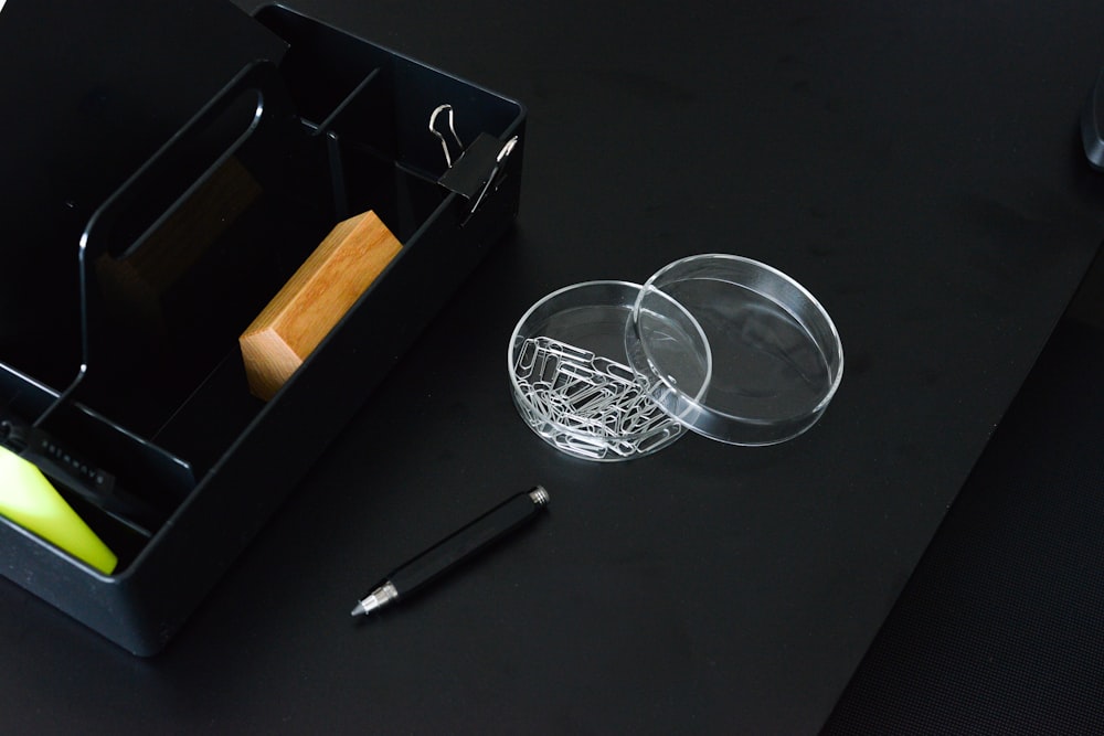 black pen beside round clear glass container and black organizer