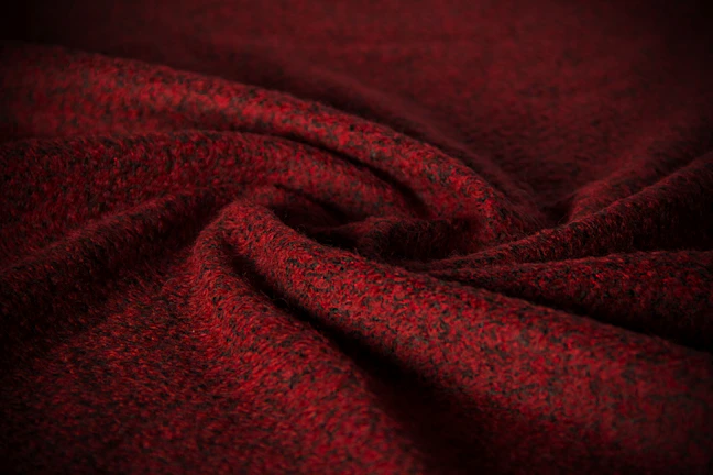 Close-up of rich, textured fabric rolls in deep jewel tones under soft lighting.
