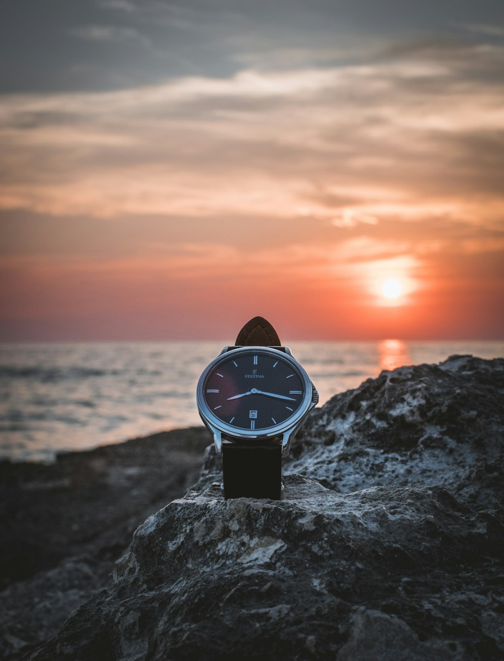 Reloj redondo de color plateado en estante durante la puesta del sol