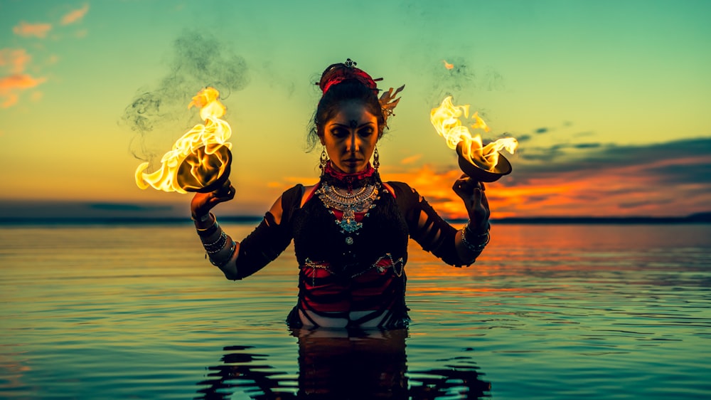 a woman holding two torches in her hands