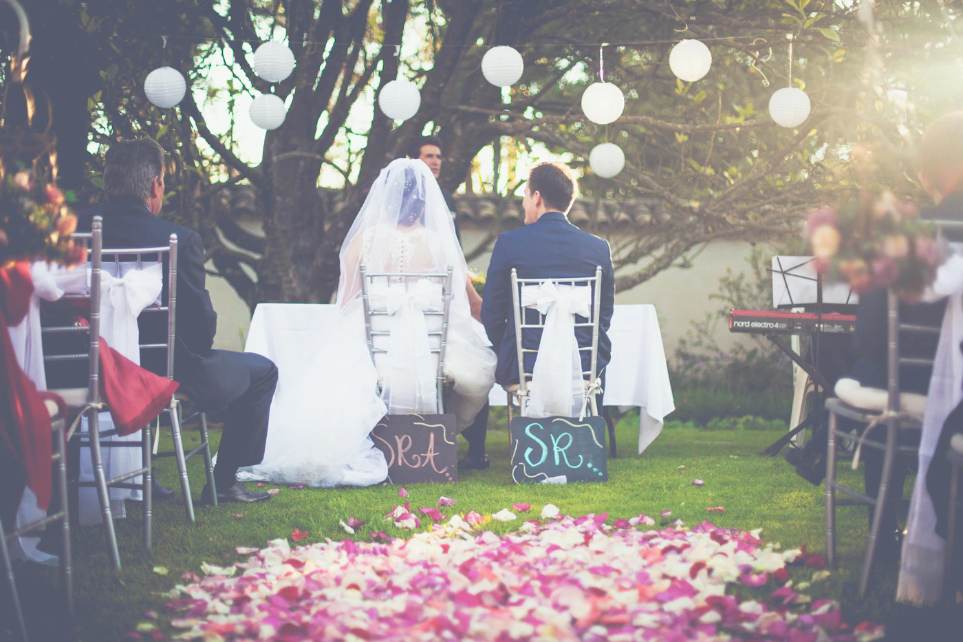 Outdoor garden wedding ceremony in Bogota Colombia with the bride and groom exchanging vows surrounded by lanterns rose petals on grass and floral arrangements
