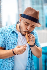 man lighting brown tobacco stick