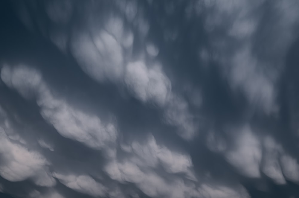 a plane flying through a cloudy blue sky