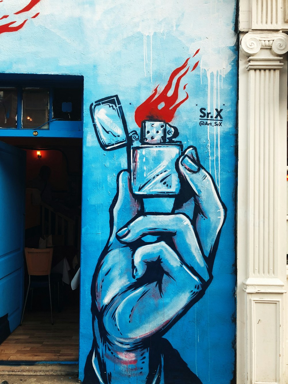 Graffiti op hand met aansteker op een blauwe muur