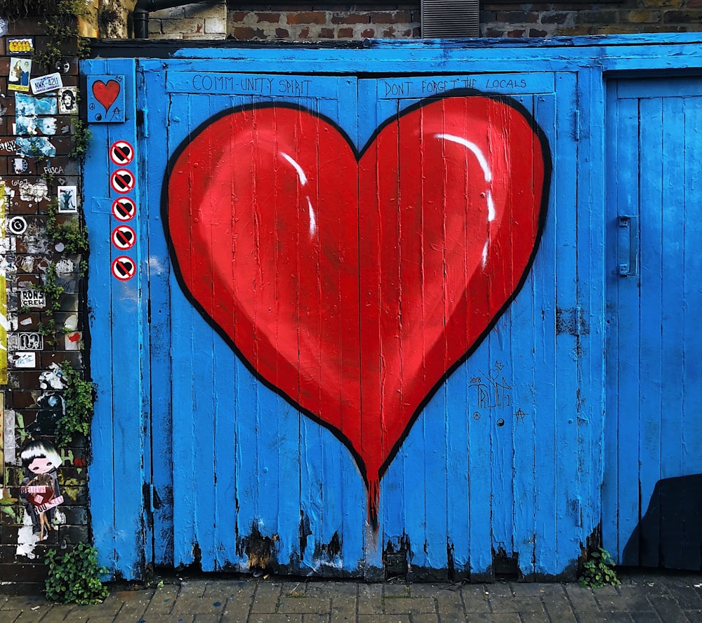 Portão de madeira azul com um coração vermelho pintado nele