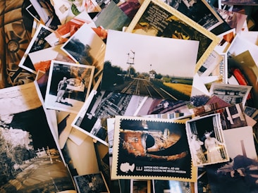 A collection of various photos and postcards scattered over a surface, featuring different scenes including railway tracks, historical landmarks, individuals, and landscapes.