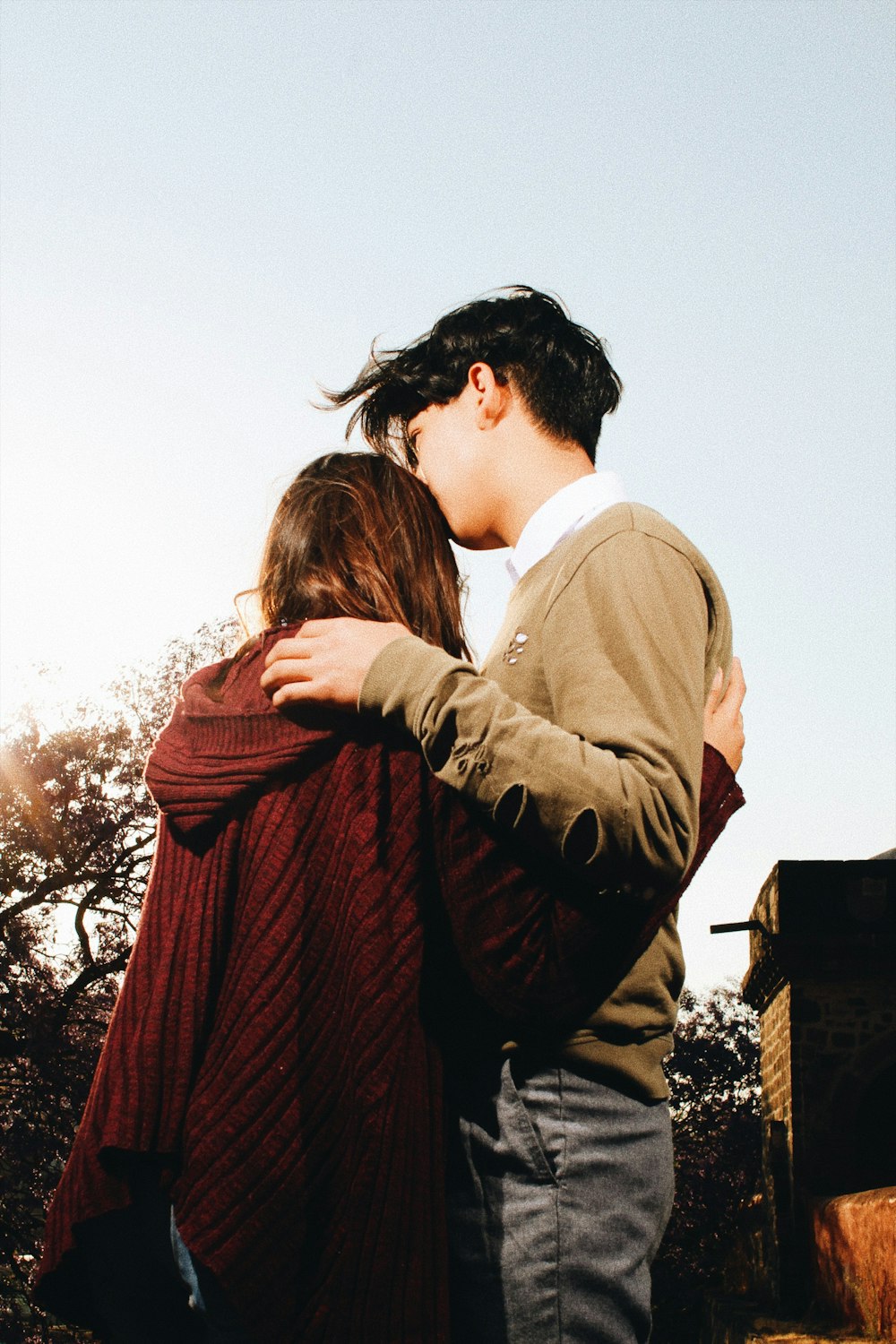 man standing beside woman and kissing forehead