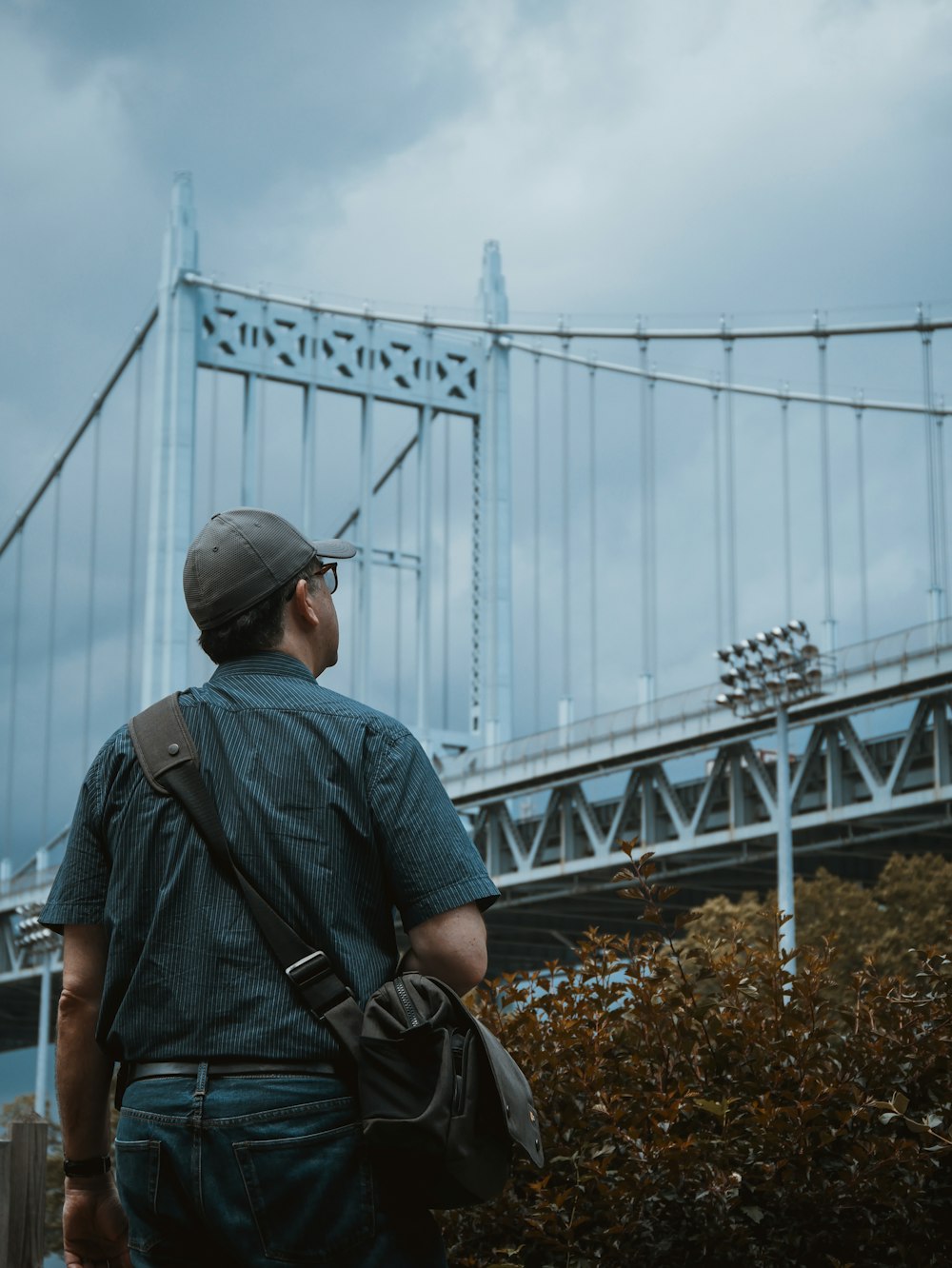 person standing and looking at gray metal bridge