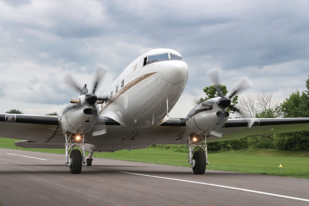 a small propeller plane on a runway with trees in the background