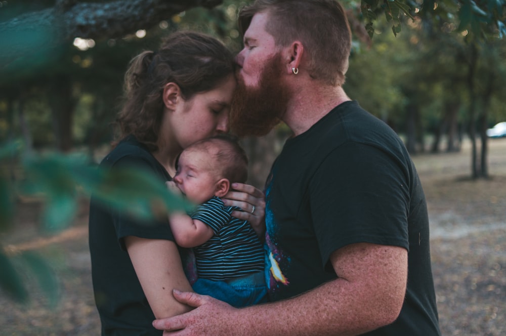 man kissing woman at forehead