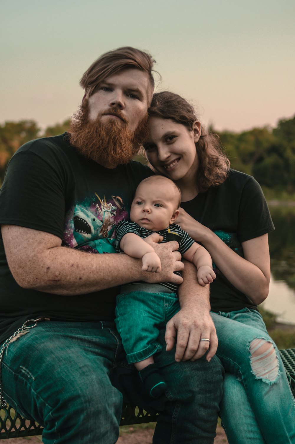 man, woman, and baby sitting on bench outdoors