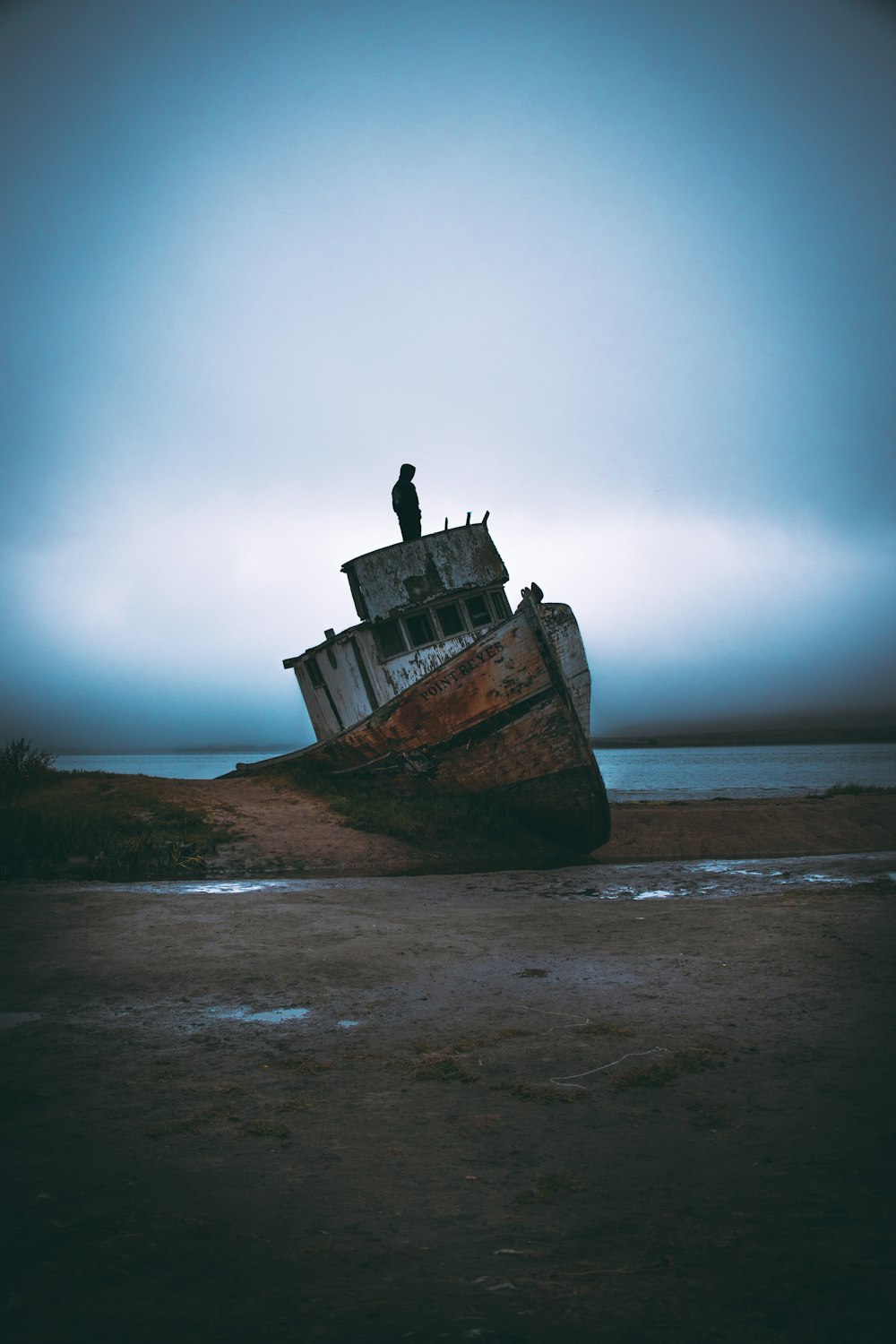 person standing on white ship wreck on beach