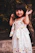 Smiling young girl twirling in a colorful boutique dress inside a bright, playful store setting.