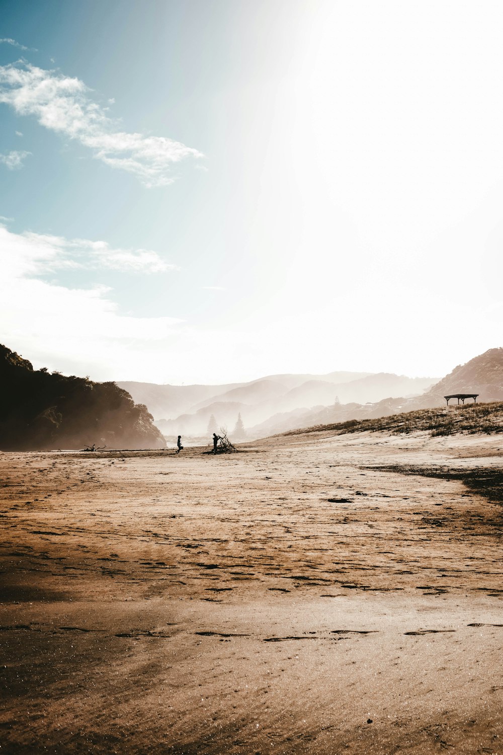 a couple of people standing on top of a sandy beach