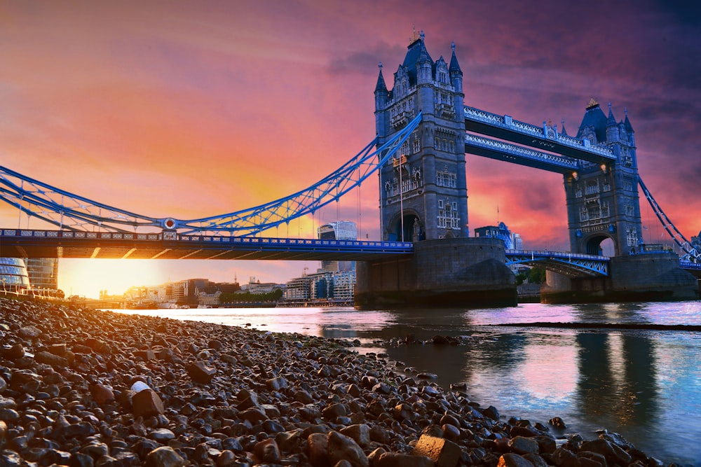 a bridge over a body of water with a sunset in the background