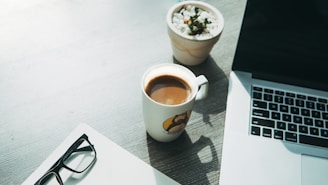 white ceramic mug beside eyeglasses