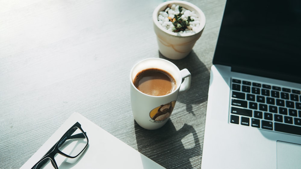 white ceramic mug beside eyeglasses