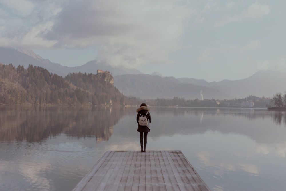 woman standing beside body of calm water