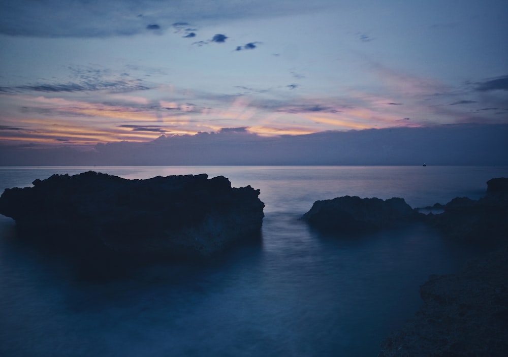 silhouette photo of rock formations on body of water