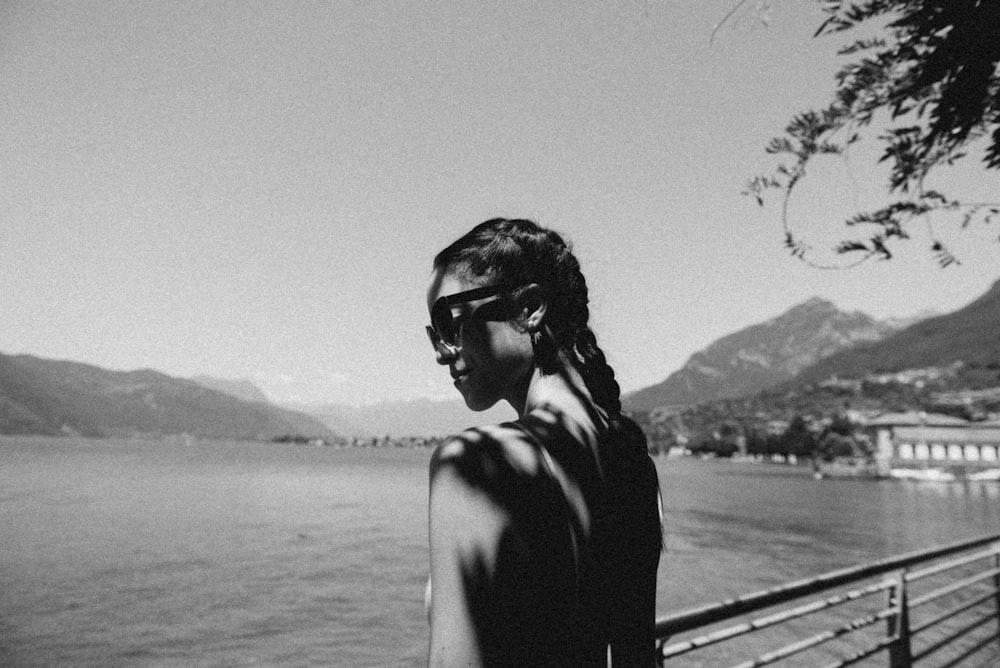 Femme debout à côté de la balustrade près d’un plan d’eau