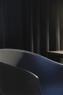 A charcoal-toned textured fabric draped over a modernist chair in natural light.