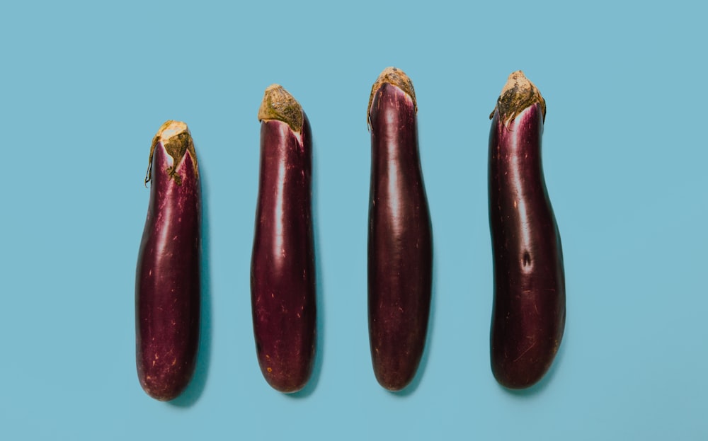 Photographie à plat de quatre aubergines violettes