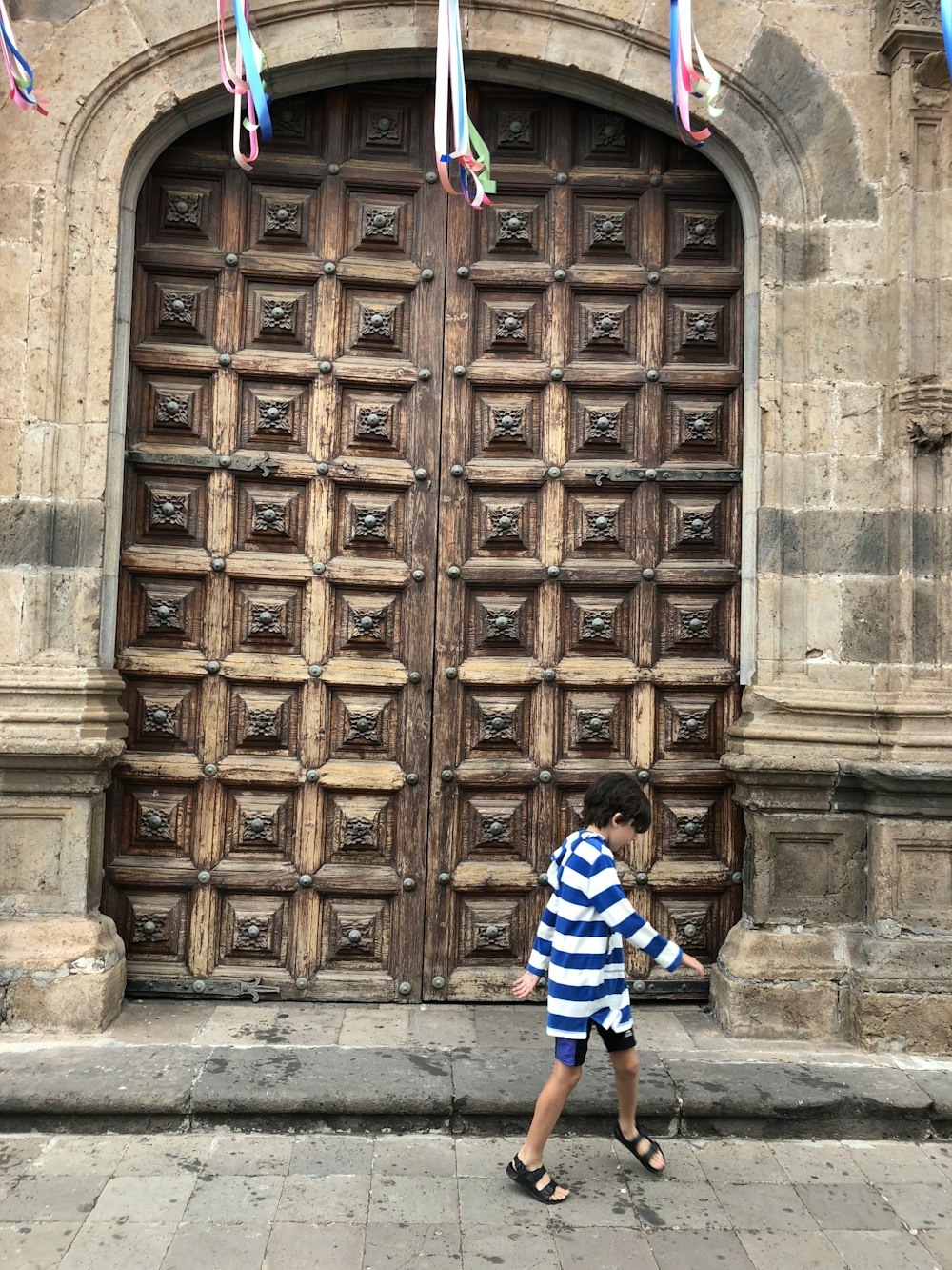 boy walking in front of brown wooden door