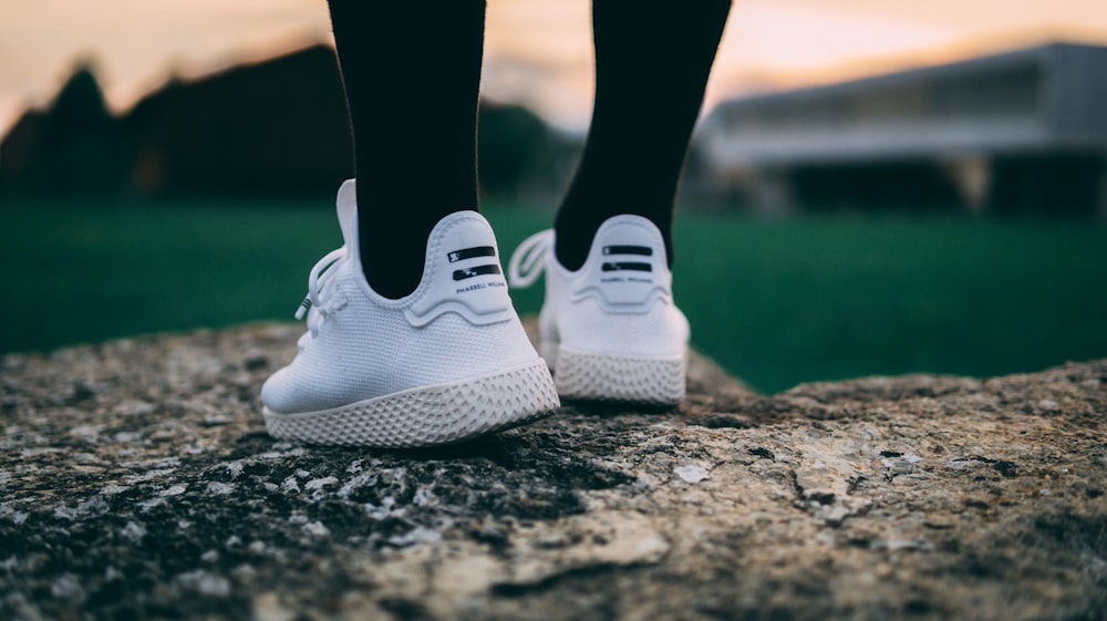 selective focus photography of person wearing shoes standing on rock